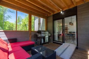 a screened in porch with a red couch and a grill at La Loutre in Chertsey