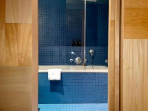 - une salle de bains carrelée de bleu pourvue d'une baignoire et d'une serviette dans l'établissement Le Citizen Hotel, à Paris
