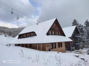 una casa cubierta de nieve junto a un remonte en Apartmán Jozef Valčianska dolina, en Lazany 4 fotos más