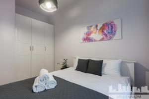 ein Schlafzimmer mit einem weißen Bett und einem Gemälde an der Wand in der Unterkunft Millennium Awangarda Grey in Warschau
