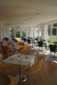 uma sala de jantar com mesas, cadeiras e janelas em EuroHotel Günzburg em Günzburg