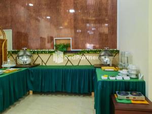 einen Tisch mit einem grünen Tischtuch in einem Zimmer in der Unterkunft Wisma Auliyah Kolaka Utara Mitra RedDoorz in Susua