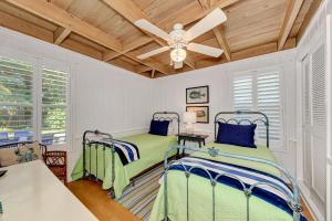 two beds in a bedroom with a ceiling fan at House of the Sun in Siesta Key