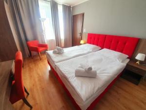 a bedroom with a red bed with two towels on it at Lux Resort in Kraśnik