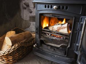 una estufa con fuego junto a una cesta en The Yorkshire Hosts - Come Home Cottage, en Haworth