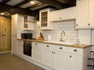 a kitchen with white cabinets and a sink at The Yorkshire Hosts - Come Home Cottage in Haworth