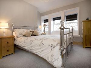 a bedroom with a bed and two windows at The Yorkshire Hosts - Come Home Cottage in Haworth
