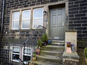 a front door of a brick house with potted plants at The Yorkshire Hosts - Come Home Cottage in Haworth