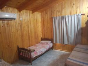 a small bedroom with a bed in a wooden cabin at Cabaña panorámica sobre el PARANÁ y Pesca in Itá Ibaté