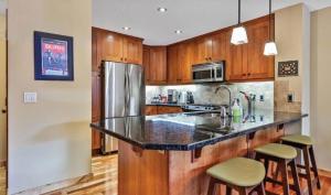 a kitchen with wooden cabinets and a stainless steel refrigerator at Luxurious Rundle Cliffs Lodge in Spring Creek in Canmore