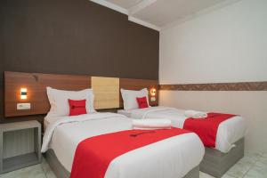 a hotel room with two beds with red sheets at RedDoorz Syariah near Kota Cinema Mall Jatiasih 