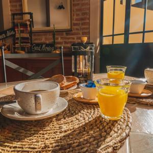 a table with a cup of coffee and a bowl of orange juice at El Arribo Hotel in San Salvador de Jujuy