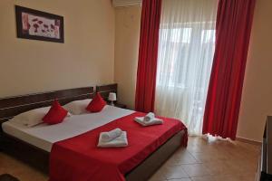 1 dormitorio con 1 cama con cortinas rojas y ventana en Vila Casa Esy, en Eforie Nord
