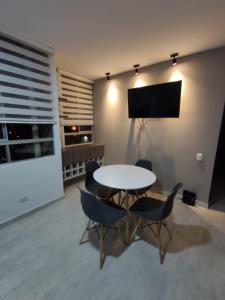 uma sala de jantar com mesa e cadeiras e uma televisão em Encantador y acogedor apto amoblado villavicencio em Villavicencio