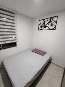 比亞維森西奧的住宿－Encantador y acogedor apto amoblado villavicencio，卧室配有一张床,墙上挂着自行车