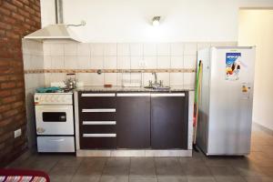La cocina está equipada con nevera, fogones y fregadero. en La Canquelera en Sierra de la Ventana
