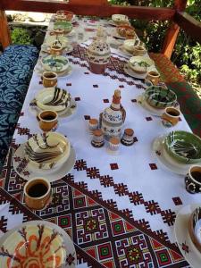 una mesa larga con platos y tazas. en Casuta Bunicilor Isverna, en Isverna