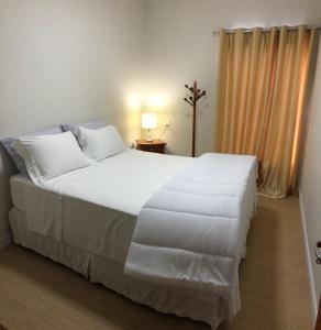 a bedroom with a large bed with white sheets at Almada Studio 77 in Cunha