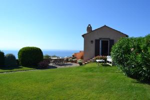 a small house with a grassy yard and the ocean at La Casa Del Faro - Bookwedo in Porto Ercole