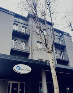 Un árbol delante de un edificio con un cartel. en Hotel Alabama by ALEhotels, en Rímini