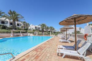 een zwembad met stoelen en een parasol bij Vila Mourisca in Porches