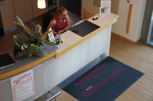 a man is sitting at a counter in a lobby at EuroHotel Günzburg in Günzburg