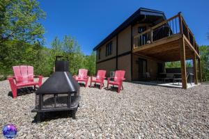 a group of red chairs and a house at Chalet le Caribou- Chalets Galaxia in Saint-Alphonse-Rodriguez