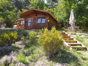 a log cabin with a table and an umbrella at Destination Ailleurs in Castellane