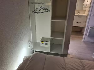 a room with a bed and a closet with a shelf at Superbe T2 climatisé, proche plage avec parking privé in Saint-Cyprien