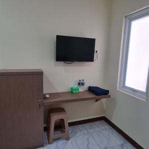 Habitación con escritorio y TV en la pared. en RedDoorz near Tugu Muda Semarang, en Kalibanteng-lor 28 fotos más