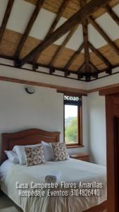 a bedroom with a large bed with a window at Casa Campestre Flores Amarillas in Villa de Leyva
