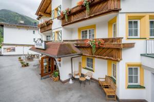 eine Außenterrasse eines Gebäudes mit Tischen und Stühlen in der Unterkunft Arlen Lodge Hotel-Garni inkl Premium Sommerkarte in Sankt Anton am Arlberg