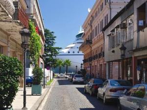 a street with cars parked on a street with a cruise ship at Guest House Lili in Batumi