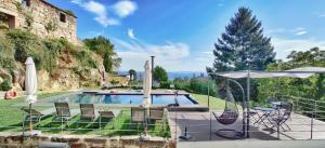 a pool with chairs and umbrellas and a tree at Paço de Vilharigues in Vouzela