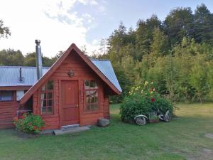un pequeño cobertizo rojo en el patio de una casa en Cabañas El Diuco en Coñaripe 2, en Coñaripe