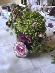 eine lila Vase mit Blumen auf dem Tisch in der Unterkunft La Ferme de Châtenoy - Le Mouton Noir in Châtenoy