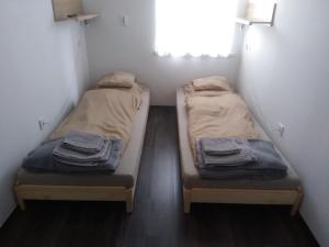two beds in a small room with a window at HZ Apartman Miskolc in Miskolc