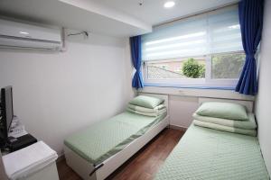 a small bedroom with two beds and a window at Namsan Guesthouse in Seoul