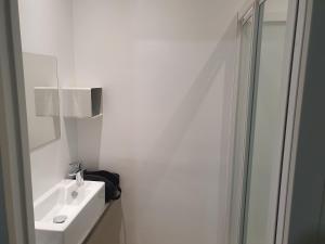 a white bathroom with a sink and a shower at Emeraude Jacuzzi in Saint Malo