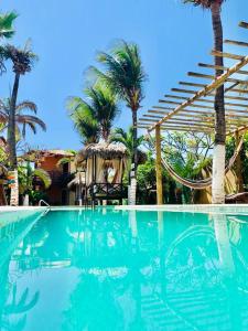 a swimming pool with palm trees and a gazebo at Ville Sweet Home in Canoa Quebrada