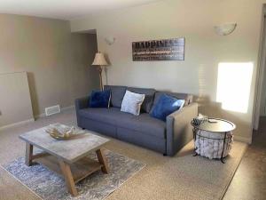 uma sala de estar com um sofá azul e uma mesa em Spacious Basement suite em Camrose