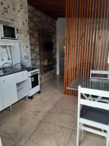 a kitchen with a stove and a sink and a table at Moradas Jeane in Guarda do Embaú