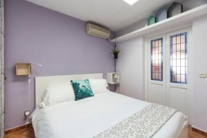 um quarto branco com uma cama branca e 2 janelas em Homelike Huertas em Madri