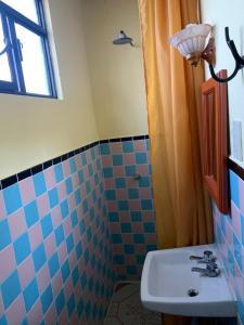 y baño con lavabo y ducha de azulejos azules. en Hotel Clasico Colonial, en Comitán de Domínguez