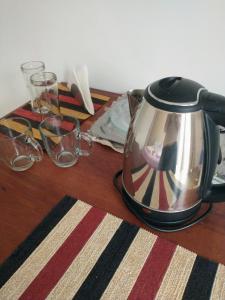 a tea kettle and glasses on a wooden table at Habitación con baño privado en edificio 1er piso in San Salvador de Jujuy