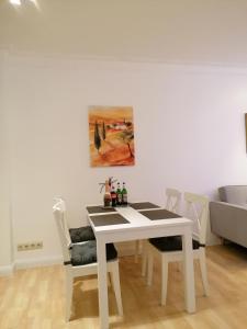 een witte eettafel met stoelen en een schilderij bij Schöne Wohnung, Zwei Schlafzimmer, Zentrumsnah, Erdgeschoss in Greifswald in Greifswald