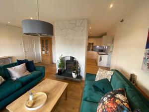 a living room with a green couch and a fireplace at The Crest Hillside Retreat With Hot Tub in Abertillery