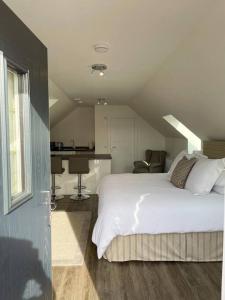 a bedroom with a white bed and a kitchen at Cosy Country Modern Studio with Patio Space. in Crieff