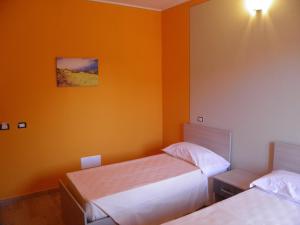 2 camas en una habitación con paredes de color naranja en B&B Mare & luna, en San Sostene