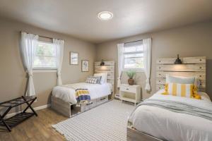 a bedroom with two beds and two windows at The Pathside Cottage in Montrose